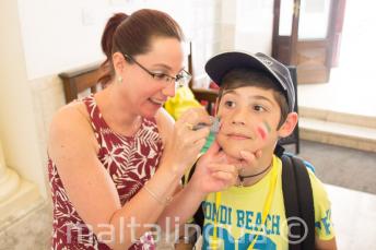 A staff member putting face-paint on a child