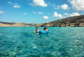 Studenci szkoły językowej pływają w wodach Blue Lagoon na Comino